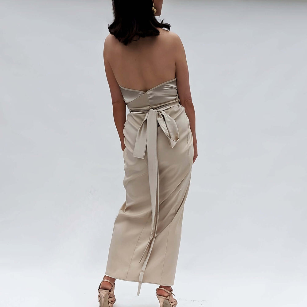 
                      
                        A woman wearing a beige dress and sandals, standing gracefully.
                      
                    