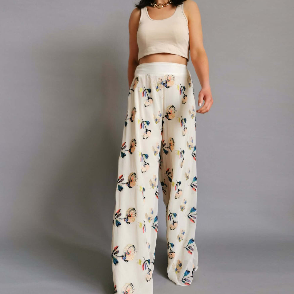 Cream and white floral print trousers worn by a model in a stylish and chic manner.