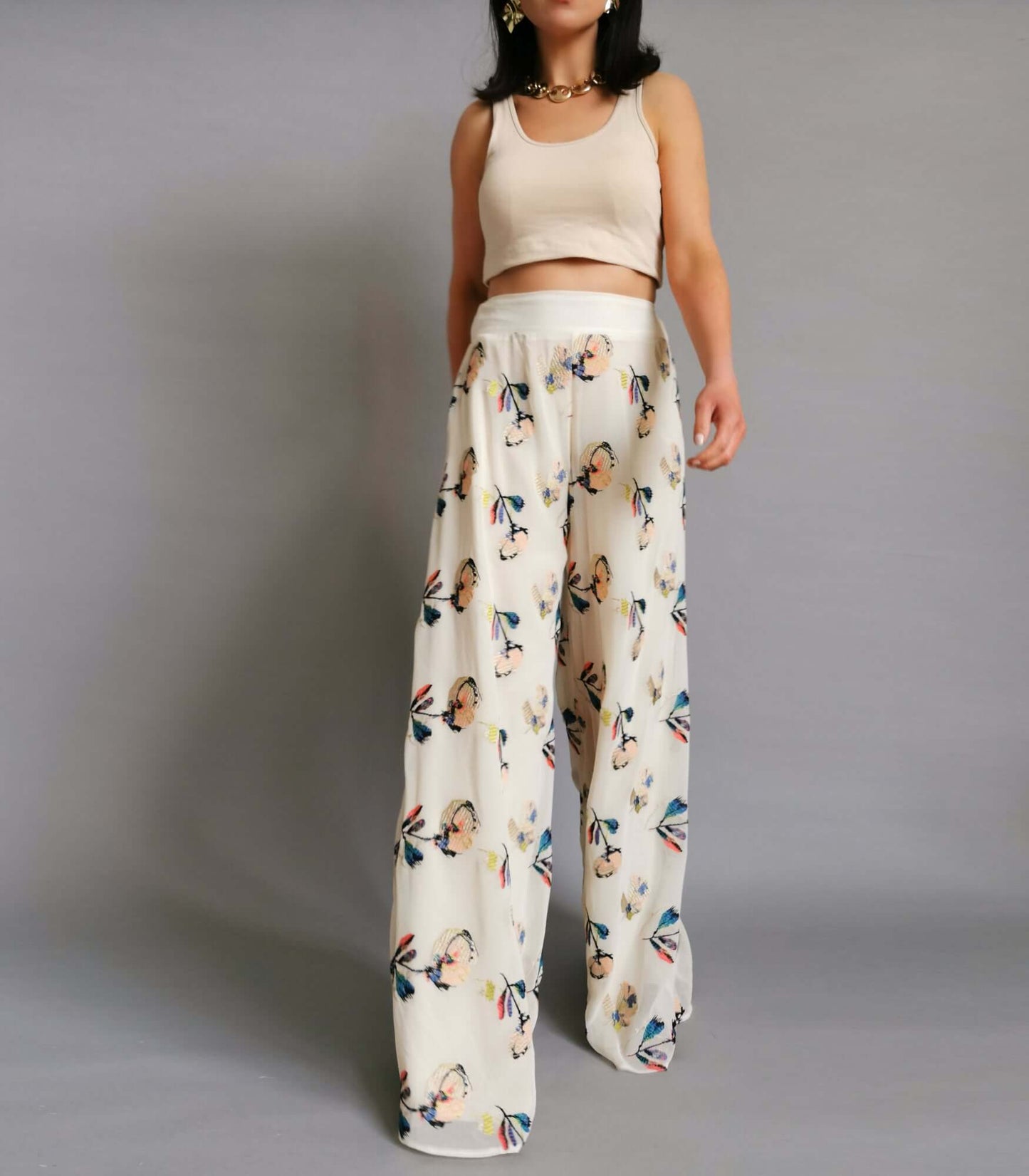 Cream and white floral print trousers worn by a model in a stylish and chic manner.