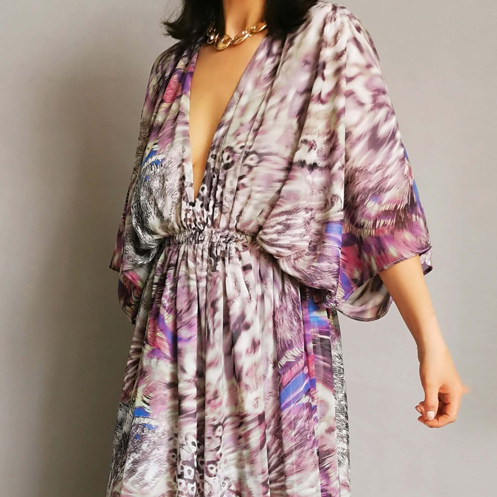 
                      
                        An elegant model showcasing a purple and pink floral print dress with style and sophistication.
                      
                    