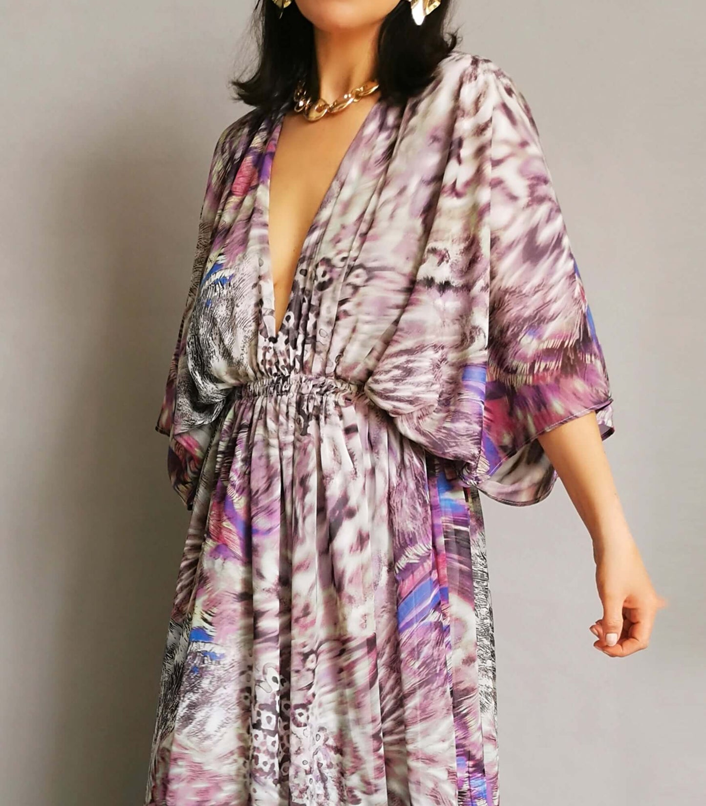 An elegant model showcasing a purple and pink floral print dress with style and sophistication.