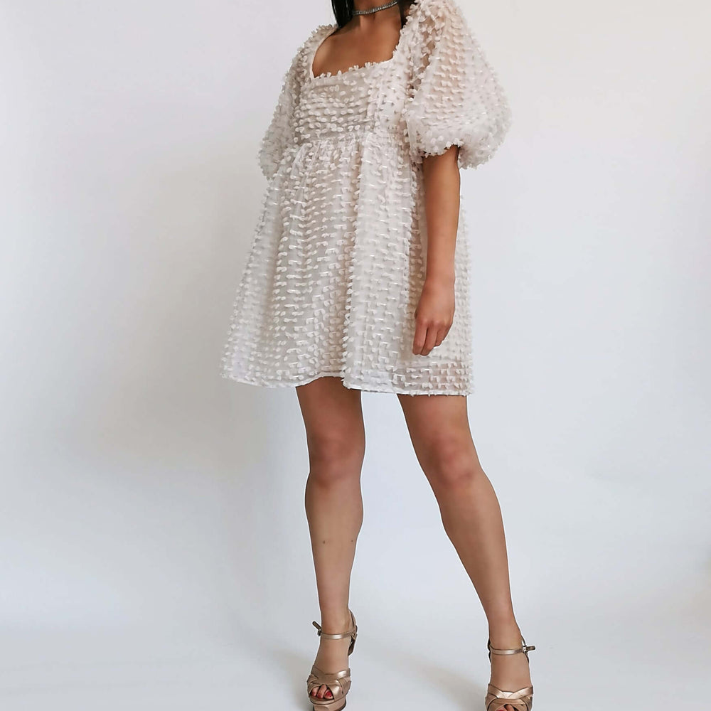 White ruffled dress worn by a model, ideal for a special occasion.