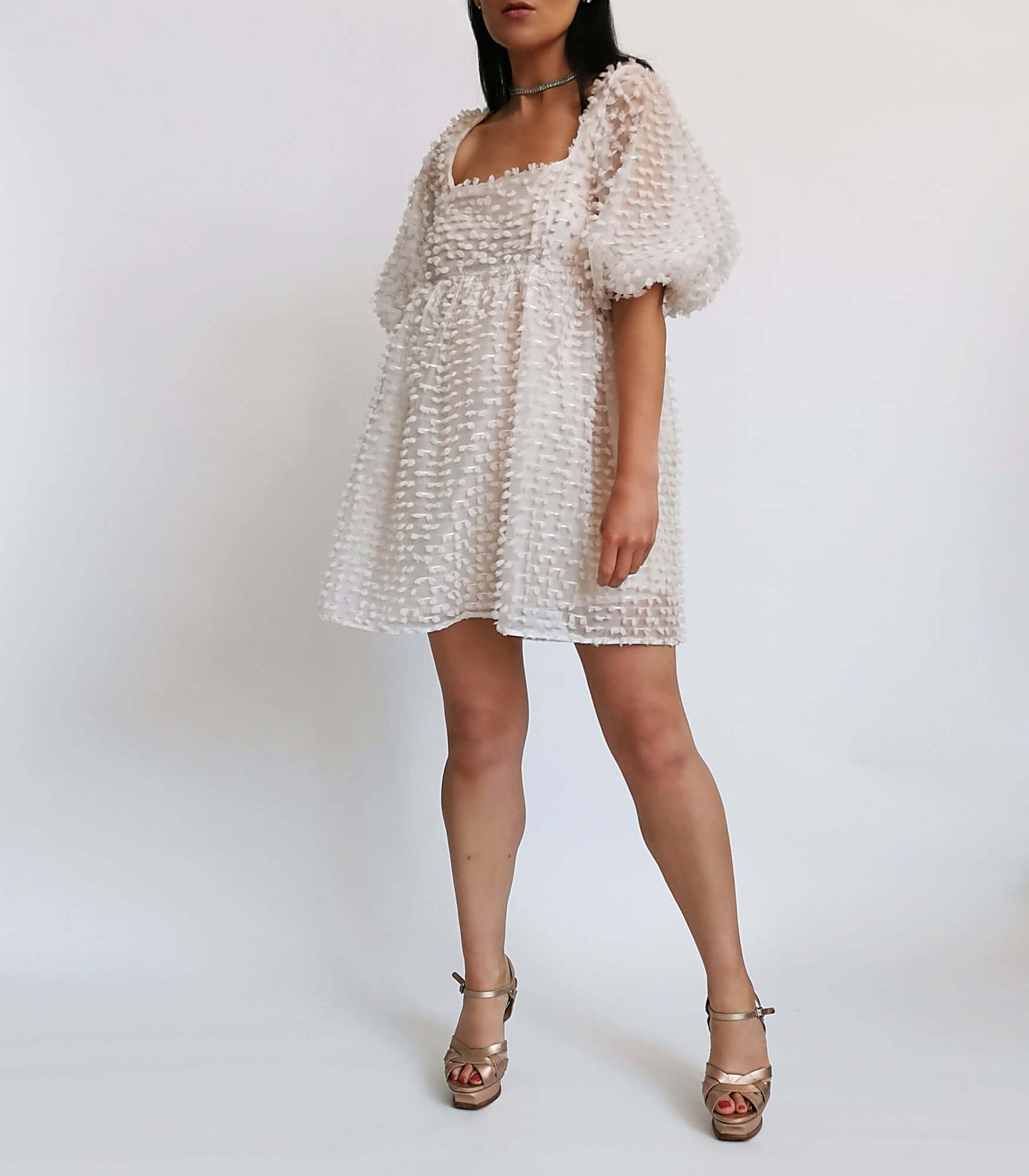 White ruffled dress worn by a model, ideal for a special occasion.