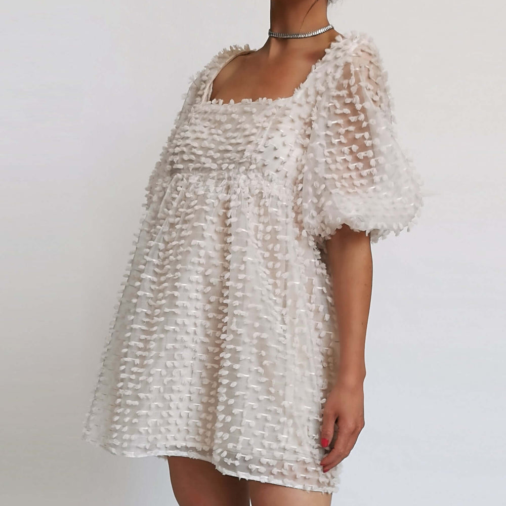  A model in a white dress with ruffles, perfect for a summer day.