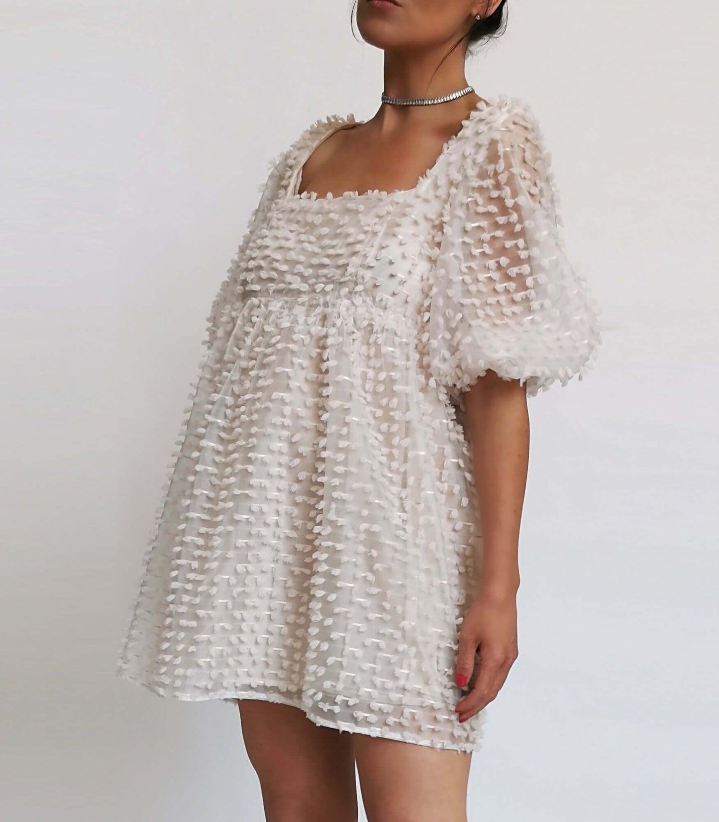  A model in a white dress with ruffles, perfect for a summer day.